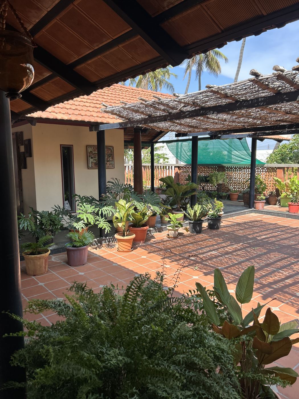 A tiled South Indian courtyard lined with potted plants