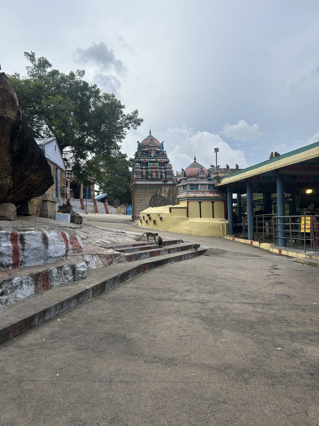 A painted temple gopuram beside a granite hillside in South India