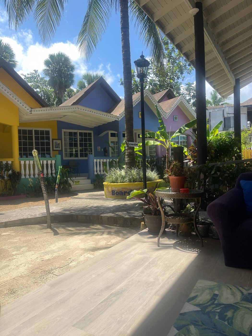 A shaded veranda and colourful cottages under palm trees in Jamaica