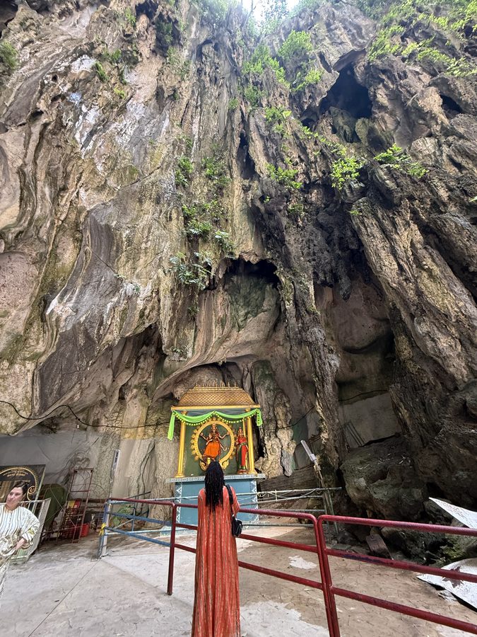 Ashleigh at a small shrine at the foot of a cave wall