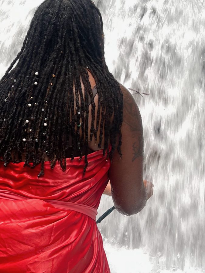 Ashleigh in red, reaching into a waterfall